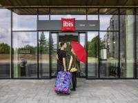 a woman with a red umbrella and a woman with a suitcase at ibis Tallinn Center in Tallinn