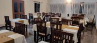 una sala da pranzo con tavoli e sedie in un ristorante di Olivia Resort and Spa a unit of Falgu Resorts Pvt Ltd a Kolār