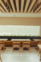 アクールにあるGrayville Hotels and Bistroのテーブルとベンチのある大きな窓のあるレストラン