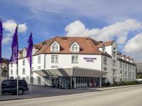 a large white building with purple flags in front of it at Mercure Hotel München Airport Freising in Freising