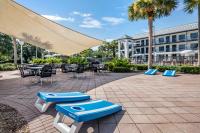 un patio con mesas, sillas y una sombrilla grande en voco Kissimmee Orlando by IHG, en Orlando