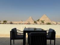 einen Tisch und Stühle mit den Pyramiden im Hintergrund in der Unterkunft Pyramids Lodge in Kairo