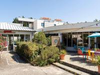 Un restaurante con mesas y sillas frente a un edificio. en greet Hotel Bordeaux Aeroport, en Mérignac