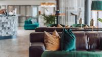 a brown leather couch with pillows in a living room at Apple Hotel &amp; Konferens Göteborg in Gothenburg