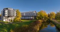 a building next to a river next to a building at Kongresshotel Potsdam am Templiner See in Potsdam