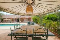 uma mesa e cadeiras debaixo de um guarda-sol ao lado de uma piscina em Dar Salah - Eddine Oasis Pool & SPA em Marraquexe