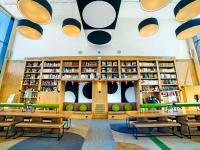 biblioteca con mesas, sillas y estanterías en ibis Styles La Roche-sur-Yon, en Mouilleron-le-Captif