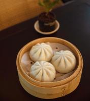 a wooden bowl with three dumplings in it on a table at Manju Hotel Zhoushan New City Children's Park Branch in Zhoushan