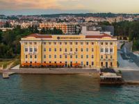 a large yellow building on the water next to a river at Hyatt Regency Zadar in Zadar