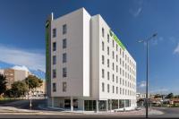 a white building with a green sign on it at B&amp;B HOTEL Setúbal Bonfim in Setúbal