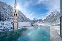 una piscina con una torre de reloj y montañas cubiertas de nieve en Hotel Stern, en Längenfeld