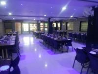 a banquet hall with tables and chairs with purple lighting at Hotel Radha Krishna in Bhusāwal