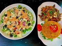 two plates of food with salad and rice on a table at 5 Star Villa Hotel in Accra