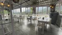 a dining room with tables and chairs and windows at Singh Saab Rooms & Cafe in Manāli