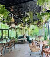 Una mujer sentada en un sofá en un patio con mesas y sillas. en Sunny Camping Sóc Sơn, en Sóc Sơn