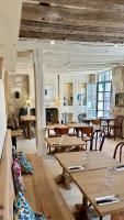 Un restaurante con mesas y sillas de madera y una cocina. en Auberge Radieuse, en Azay-le-Rideau