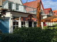 Exclusive FEWO in Warnemünde, 150m to the beach, 2 bathrooms, 2 bedrooms, sauna, WiFi and much more. في روستوك: مطعم ذو مظلة خشبية أمام مبنى