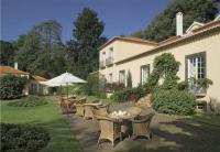 eine Terrasse mit Tischen und Stühlen und einem Sonnenschirm in der Unterkunft Luxury Villa Pembe Palheiro Village by Holiday Rental Madeira in Funchal