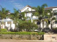 Una gran casa blanca con palmeras delante. en Hotel Providencia, en Mariana