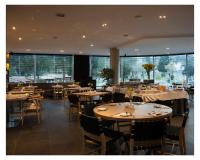 un ristorante con tavoli e sedie in legno e grandi finestre di Casa Grande Suites a La Paz