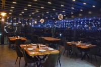 a restaurant with wooden tables and chairs and lights at Bujtina Oxhaku in Peshkopi