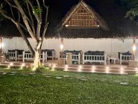 Un grupo de mesas y sillas debajo de una choza de paja. en Jumeirah Malindi Hotel, en Malindi