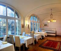 Un restaurante con mesas y sillas blancas y ventanas. en Bresbot B&B, en Bressana Bottarone