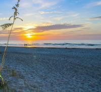 einen Sonnenuntergang am Strand mit Sonnenuntergang in der Unterkunft The Resort on Cocoa Beach in Cocoa Beach