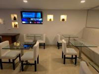 Una sala de espera con mesas y sillas y un televisor. en Hotel Castellana 95 Bogota By Hoteles Confort 80, en Bogotá