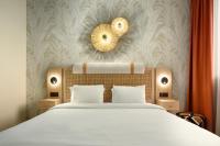 Un dormitorio con una cama y un espejo en la pared. en Radisson Hotel Clermont-Ferrand, en Clermont-Ferrand