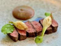 a piece of meat with a nut and some green leaves at Romantik Waldhotel Mangold in Bergisch Gladbach