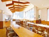 a restaurant with wooden tables and chairs and large windows at 湯宿くったり温泉 レイクイン in Shintoku