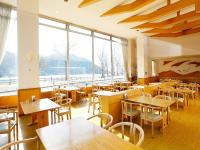 a restaurant with tables and chairs and a large window at 湯宿くったり温泉 レイクイン in Shintoku