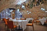 a restaurant with white tables and chairs and a brick wall at Hotel San Giovanni Resort in Saluzzo