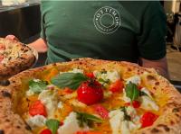 eine Person in einem grünen Hemd hält zwei Pizzen in der Unterkunft studio gabriel in Bastia