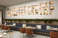 Four Points by Sheraton Kinshasa في Kinshasa: مطعم بطاولات وكراسي وجدار وصحون