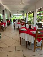 a restaurant with tables and chairs with red tablecloths at Hôtel Éden Roc Ivoire in San-Pédro