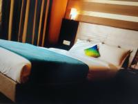 a hotel room with a bed with a colorful pillow at Hotel Shiv in Bahādrābād