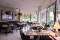 Un restaurante con mesas y sillas y grandes ventanales. en Badehaus Hotel & Restaurant, en Neubrandenburg