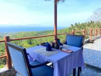 Paradisehill Nusa Penida Resort في نوسا بينيدا: طاولة وكراسي على شرفة مطلة على المحيط