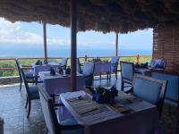 Paradisehill Nusa Penida Resort في نوسا بينيدا: مطعم به طاولات وكراسي مع المحيط في الخلفية