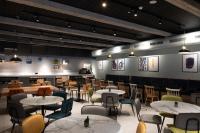 Un restaurante con mesas y sillas en una sala. en voco Bilbao - City by IHG, en Bilbao