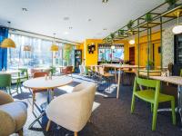 Un restaurante con paredes amarillas, mesas y sillas. en Novotel Saint Avold, en Saint-Avold