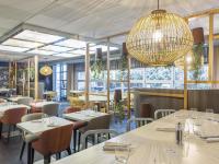 Un restaurante con mesas y sillas y una lámpara de araña. en Mercure Paris Massy Gare TGV, en Massy