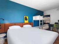 Un dormitorio con una cama blanca y una pared azul. en ibis Auch, en Auch
