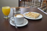 een kop koffie, een bord pannenkoeken en een glas sinaasappelsap bij Che Argentina Hostel Suites in Buenos Aires