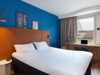 Un dormitorio con una cama blanca y una pared azul. en ibis Lyon Sud Vienne Saint-Louis, en Vienne