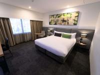 ペンリスにあるMercure Penrithの大きなベッドと机があるホテルの部屋
