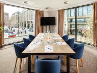 a conference room with a long wooden table and blue chairs at ibis Cambridge Central Station in Cambridge