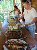 Paroá Amazon Lodge في Manacapuru: امرأة تقف أمام طاولة مع الطعام